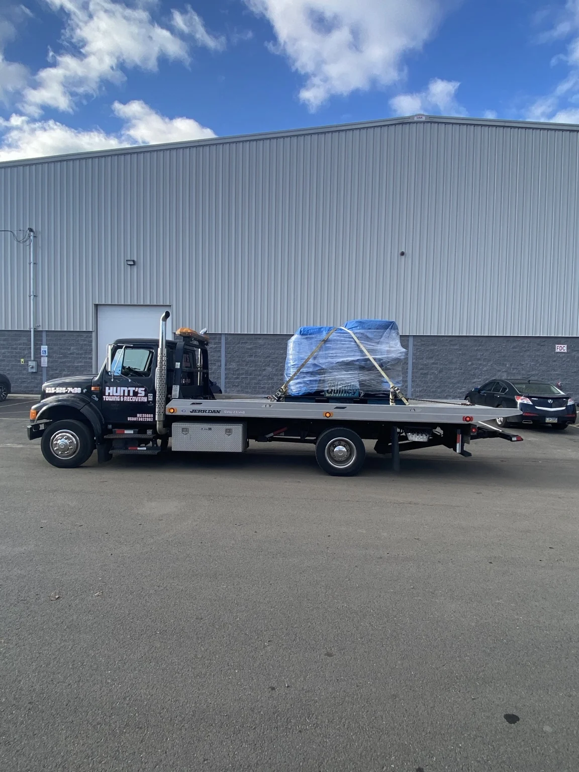 Wrapped equipment secured on the Hunt’s flatbed outside a warehouse